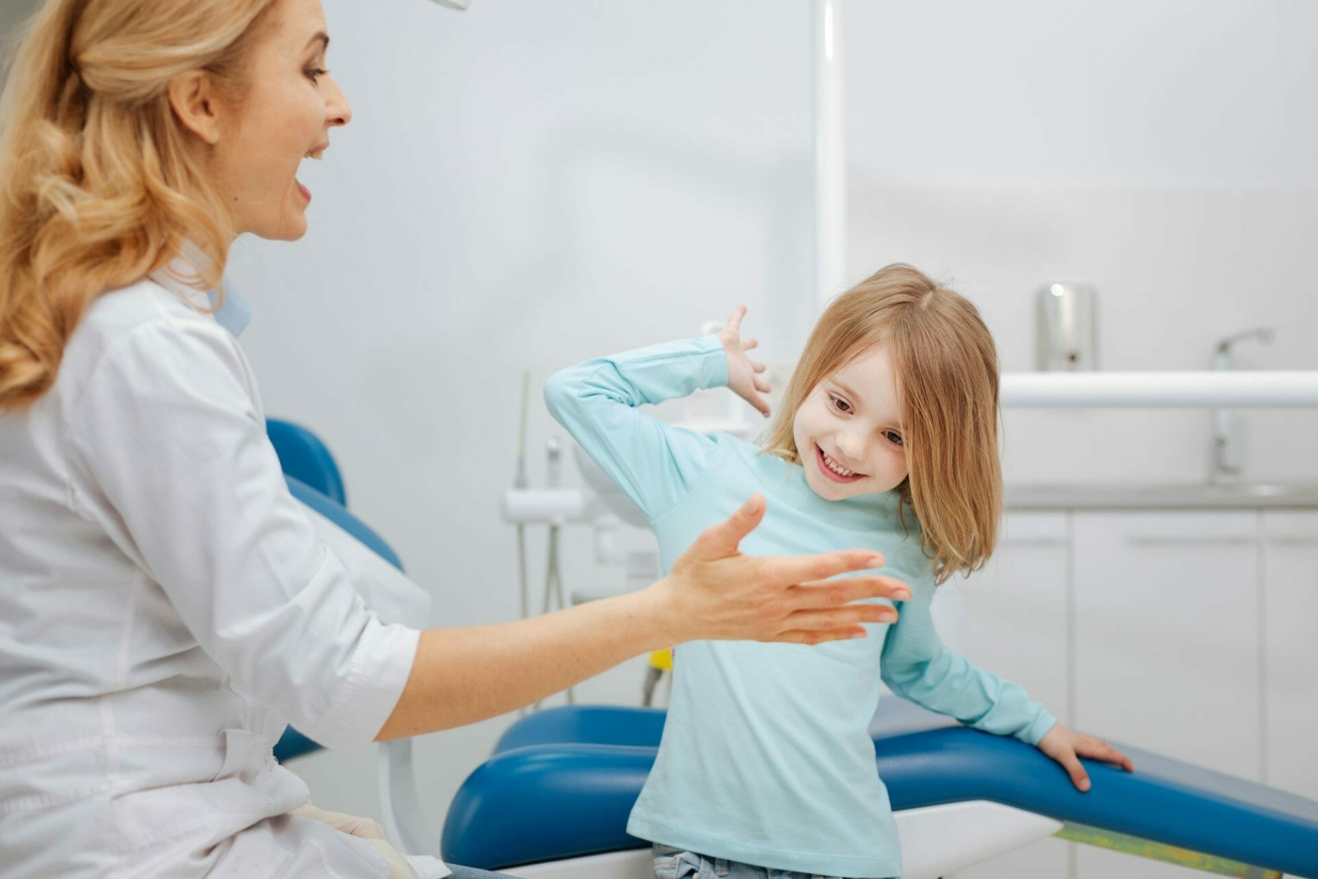 Una niña está sentada en la silla del dentista.