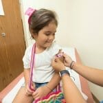 Una niña recibe una vacuna en el consultorio de un médico.