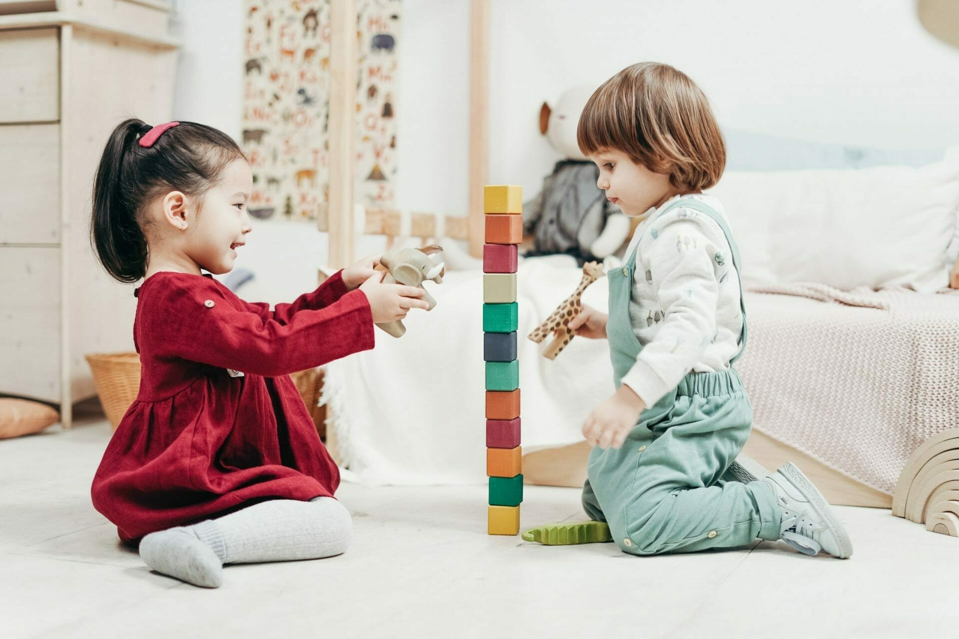 Dos niños jugando con bloques de madera en una habitación.