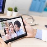 Un pediatra usa una tableta para ver un vídeo de su familia.