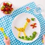 Un plato con una jirafa y fresas que proporciona nutrición experta a los niños.
