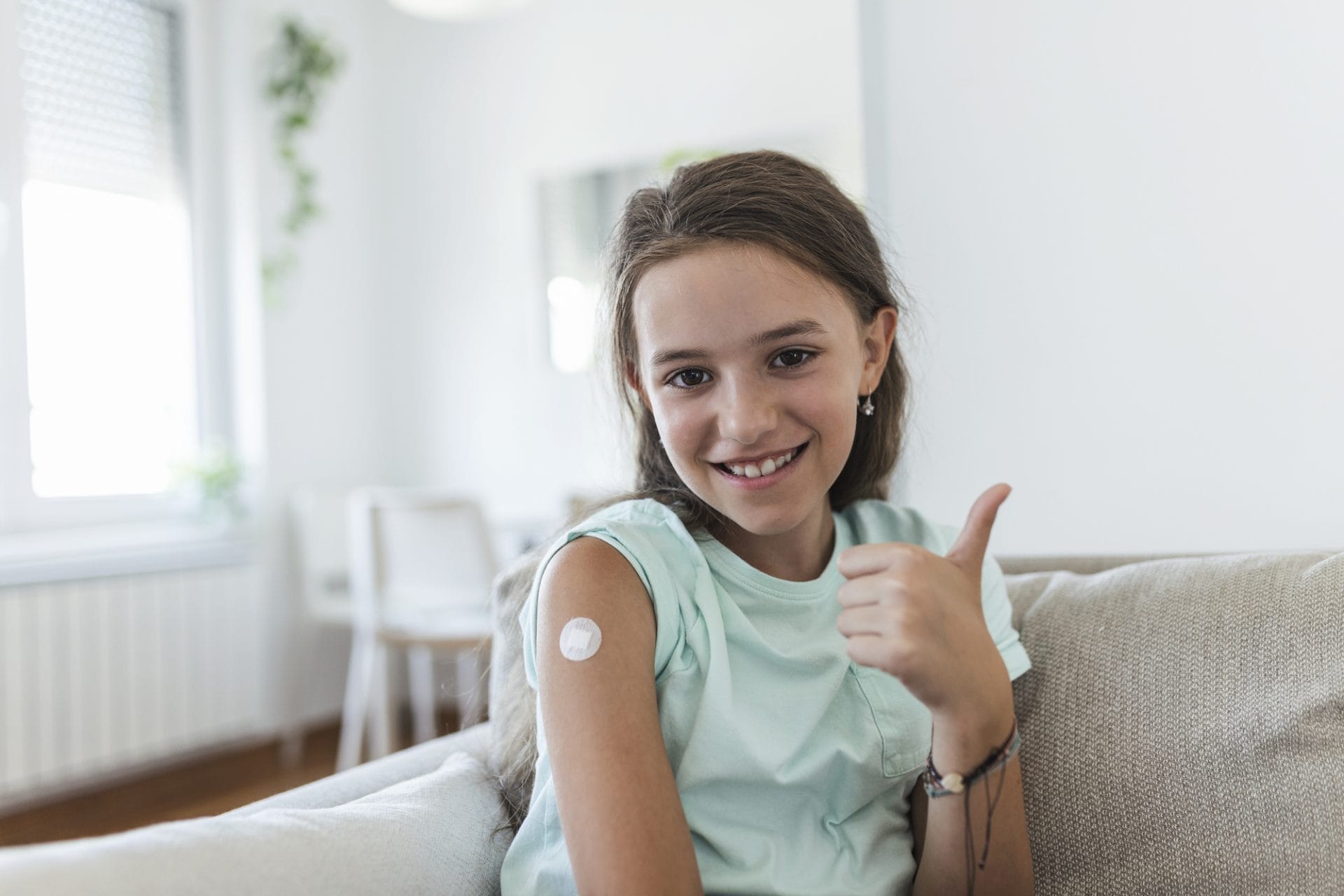 Una niña está sentada en un sofá en el suroeste de Houston y levanta el pulgar.