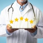 Un médico especialista en pediatría en el suroeste de Houston sostiene una tableta que muestra reseñas de cinco estrellas.