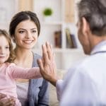 Una mujer y su hija están sentadas en un sofá con un pediatra, comunicándose eficazmente.