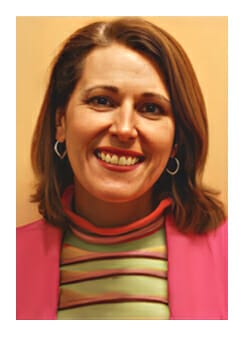 Un retrato de Jennifer Macia con una chaqueta rosa y un suéter verde.
